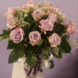 Bouquet of pale lavender roses in a glass vase with white ribbon
