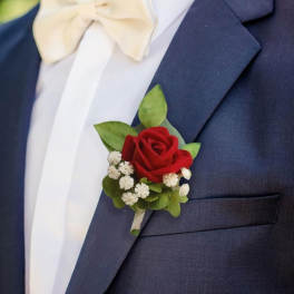Red rose boutonniere on a navy suit with a white bow tie