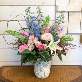 Mixed bouquet in a white patterned vase with pink, blue, and white flowers