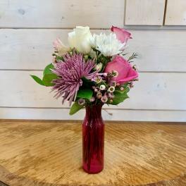 Pink and white mixed bouquet in a red glass vase