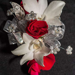 Red roses and white orchids with silver decorative accents on black fabric
