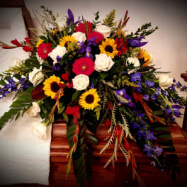 Large mixed floral spray with roses, sunflowers, and purple blooms