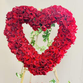Heart-shaped red rose arrangement on a wooden easel