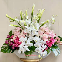 Pink roses and white orchids in a white container