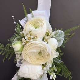 White ranunculus corsage with ribbon and greenery