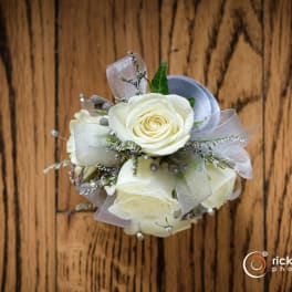 Small bouquet of white roses with silver ribbon on a wood surface