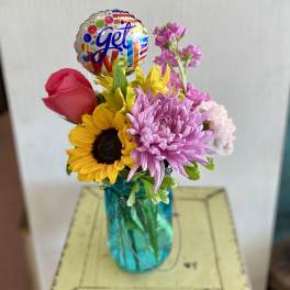Mixed bouquet in a blue vase with a colorful balloon