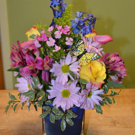 Colorful mixed bouquet in a blue glass vase with a butterfly decoration