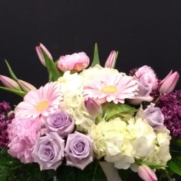 Pink and lavender flowers arranged in a white pot