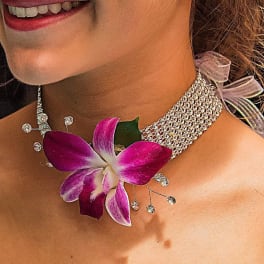 Woman wearing a purple orchid necklace and jeweled earrings