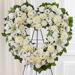 Heart-shaped white floral wreath on an easel with a ribbon bow