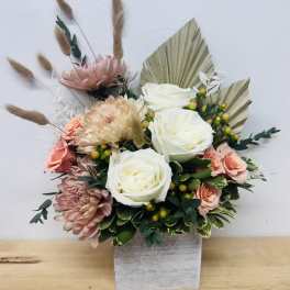 Bouquet of white and blush flowers in a square vase with dried grasses