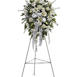 White floral standing spray on an easel with ribbon streamers