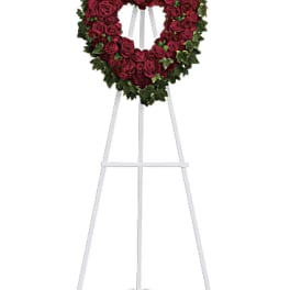 Heart-shaped red rose wreath on a white easel stand