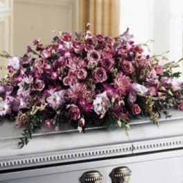 Large pink and purple floral spray on a white casket
