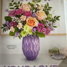 Bouquet of peach roses, purple mums, and lavender filler in a purple vase
