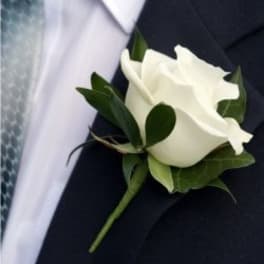 White rose boutonniere on a dark suit jacket