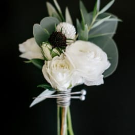 Small white floral boutonniere with eucalyptus on a black background