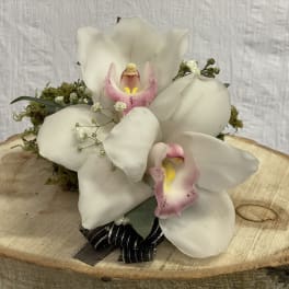 White orchid arrangement with pink centers on a wood slice