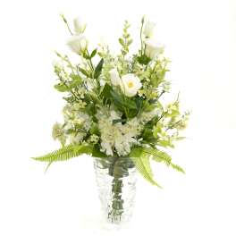 White floral arrangement in a clear glass vase with fern accents