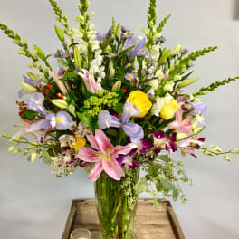 Mixed bouquet of lilies, roses, and orchids in a glass vase
