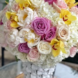 Bouquet of pink, white, and yellow flowers in a clear vase
