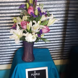Pink roses and white lilies arranged in a purple vase