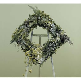 Large floral wreath on a stand with yellow and white flowers