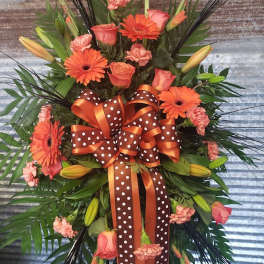 Orange gerbera daisies and roses in a large ribboned floral spray
