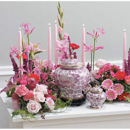 Pink floral arrangement with candles and decorative urns on a table