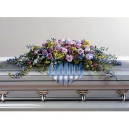 Pastel floral casket spray with roses and blue flowers