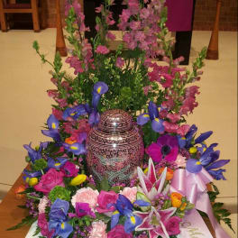 Colorful floral arrangement around a decorative urn in a church setting