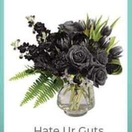 Black floral arrangement in a glass vase with green foliage