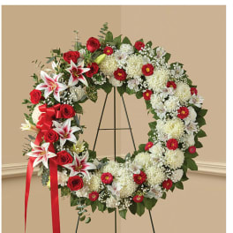 Large floral wreath with red roses and white lilies on a stand