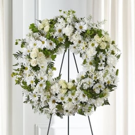 White floral wreath on a black stand
