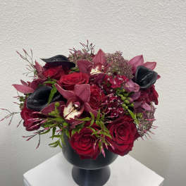 Red and burgundy floral arrangement in a black vase