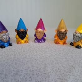 Five small colorful gnome figurines lined up on a tabletop