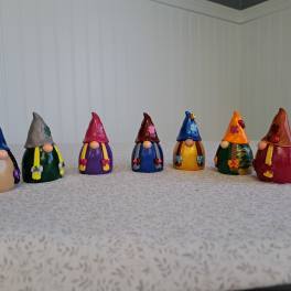 Seven small painted gnome figurines lined up on a tabletop