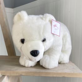 White plush polar bear with a price tag on a wooden shelf
