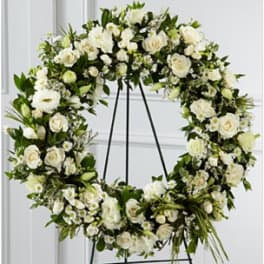 Large white rose and daisy wreath displayed on a metal easel stand.