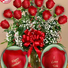 Red roses with baby’s breath in a glass vase and red ribbon