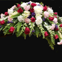 Casket spray with red and white roses, pink carnations, and greenery