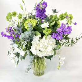 Purple and white flowers arranged in a clear glass vase