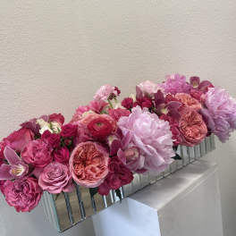 Pink and lavender floral arrangement in a mirrored rectangular vase