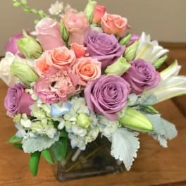 Bouquet of pink and purple roses with white lilies in a glass vase
