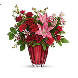 Red roses and pink lilies arranged in a red vase