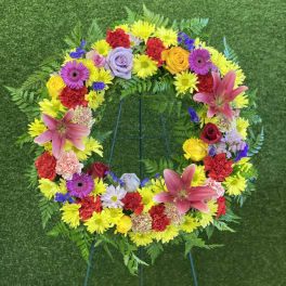 Colorful floral wreath with lilies, roses, and daisies on a stand