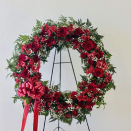Red rose wreath on a black stand with a pink bow