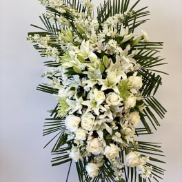 Tall white floral standing spray with roses and lilies on a stand