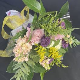 Bouquet of pink and purple flowers wrapped in clear plastic with a yellow ribbon